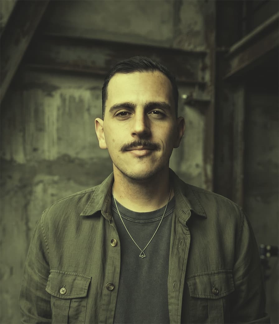 Lucas Almeida, fotografado diante de uma parede de concreto desgastada.